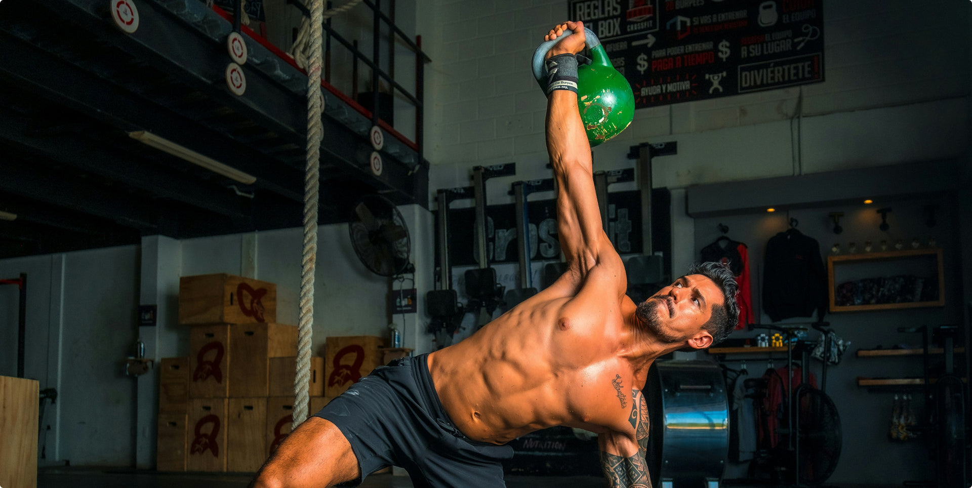 Man lifting a green kettlebell in a gym setting