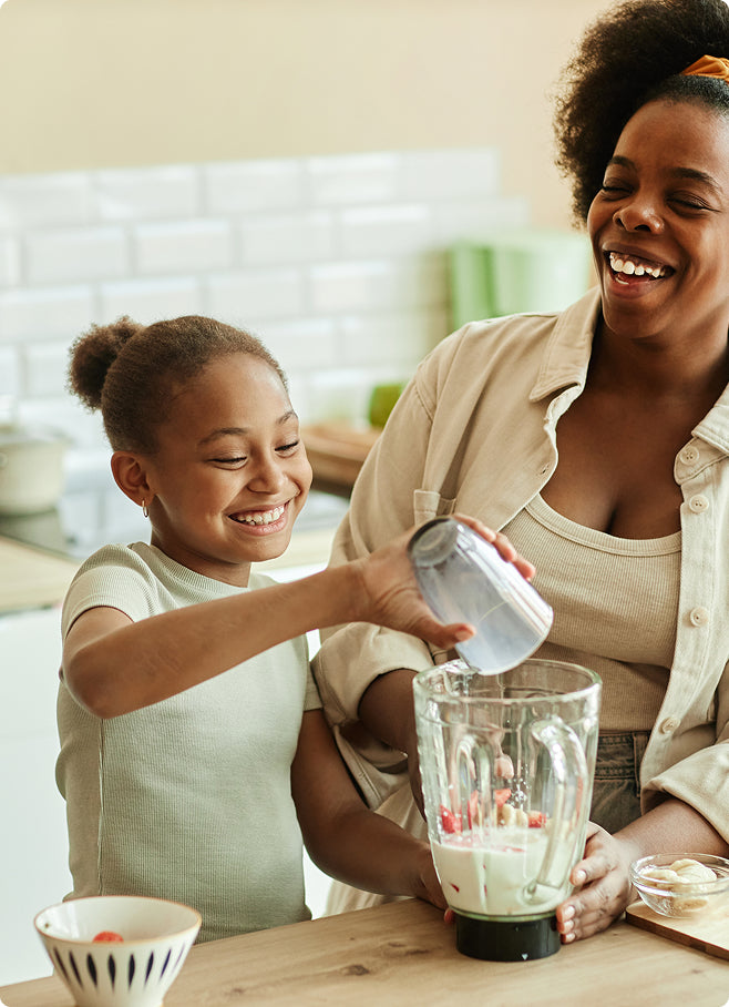 Woman and young girl preparing a smoothie in a kitchen