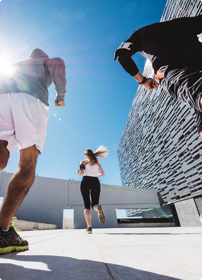 Two people running on a sidewalk with a modern building in the background