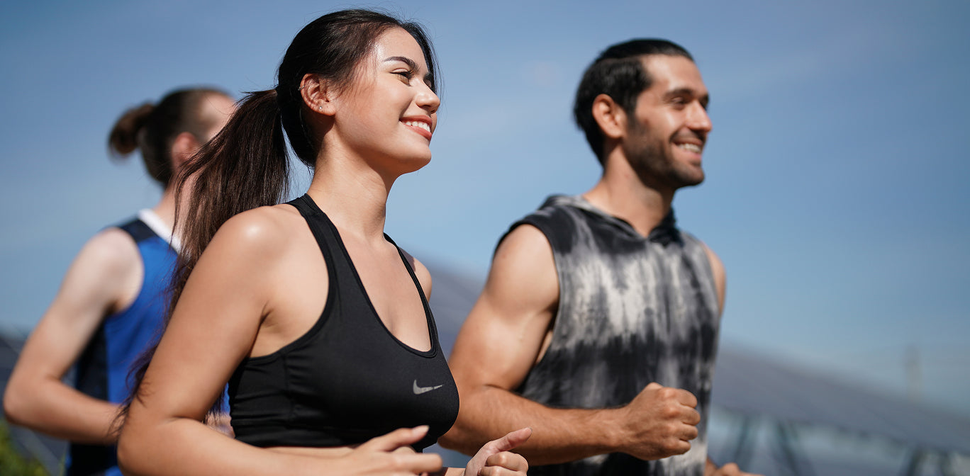 Two people running outdoors with a clear blue sky in the background